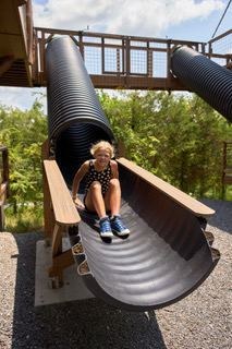 Child sliding down the outdoor slide at a TreeFort treehouse at Sanctuary Treehouse Resort